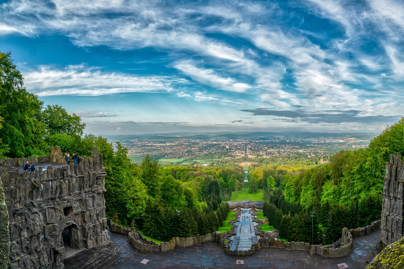 Blick auf Kassel durch Bäume und ein antikes Gebäude.