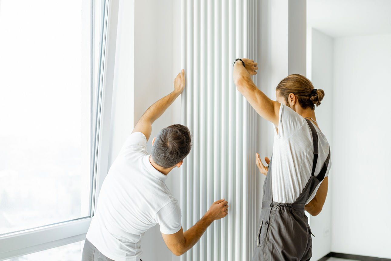 Zwei Personen die zusammen eine Heizung anbringen an die Wand