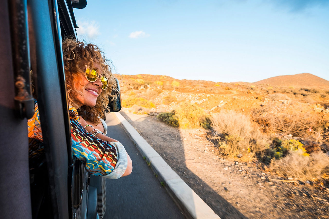 Frau mit Sonnenbrille schaut aus Autofenster