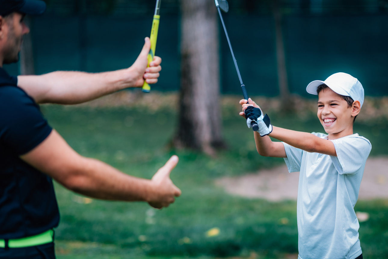 Vater und Sohn schlagen Golfschläger gegeneinander