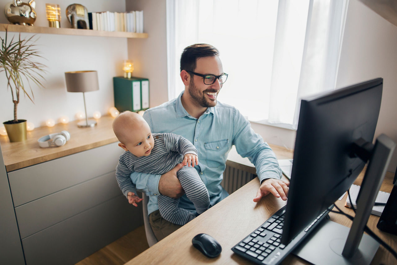 Vater mit Baby im Home Office am Schreibtisch