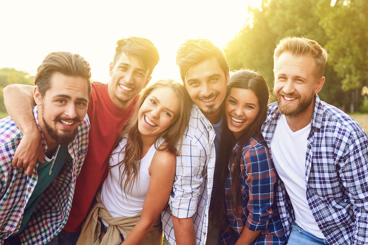 Eine Gruppe junger Menschen steht auf einer Wiese an einem See