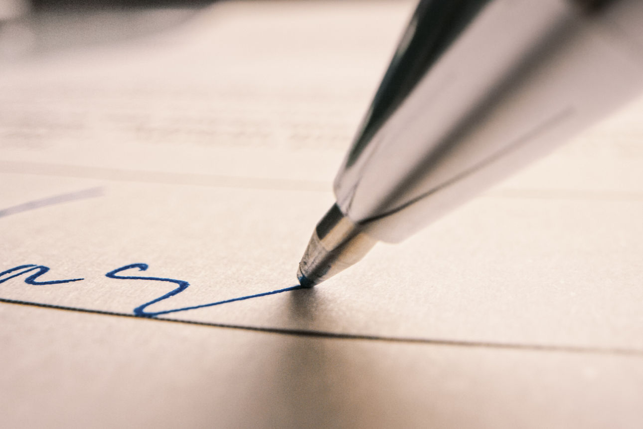 Ein Vertrag wird mit einem Kulli unterschrieben.