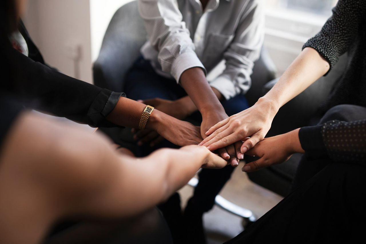Viele Hände stapeln sich übereinander in einem Teammeeting