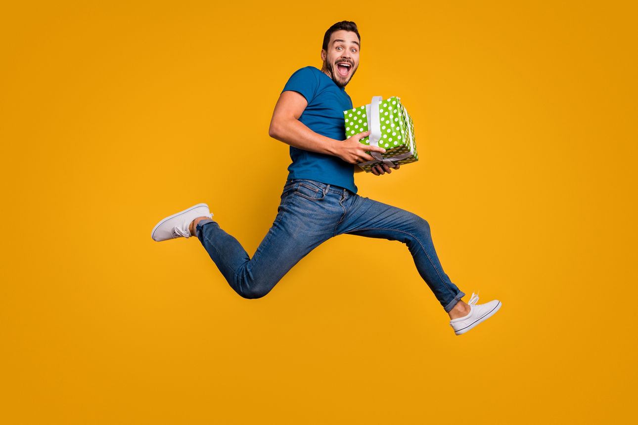 Full length body size view of his he nice attractive crazy overjoyed, cheerful cheery guy jumping holding in hands giftbox isolated over bright vivid shine vibrant yellow color background