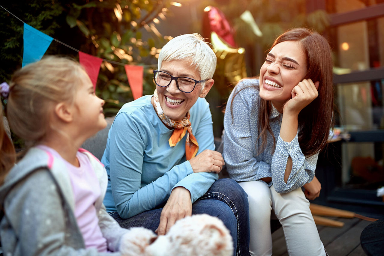 Frauen aus drei Generationen lachen bei einer Party gemeinsam