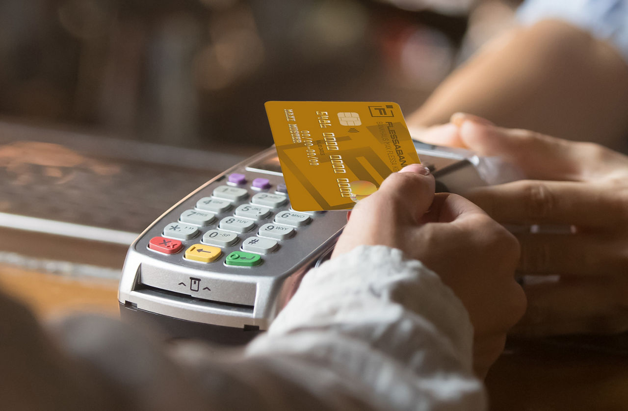 Eine Hand hält die Flessabank Mastercard BusinessCard zum Lesegerät