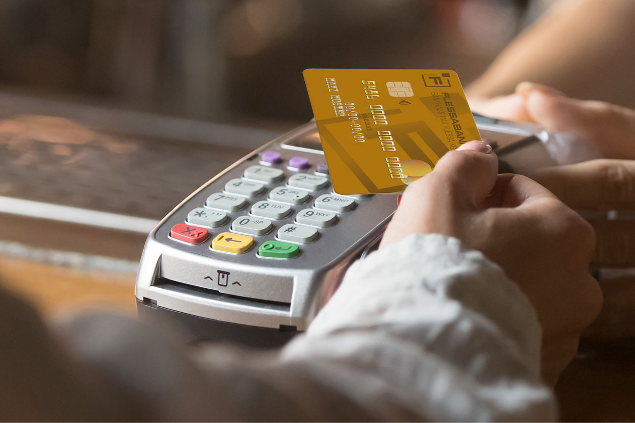 Eine Hand hält die Flessabank Mastercard BusinessCard zum Lesegerät