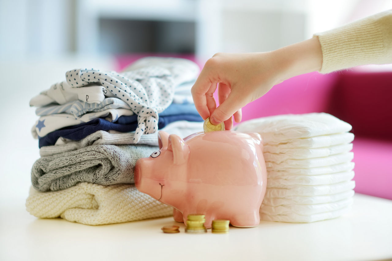 Sparschwein mit Windeln und Babykleidung