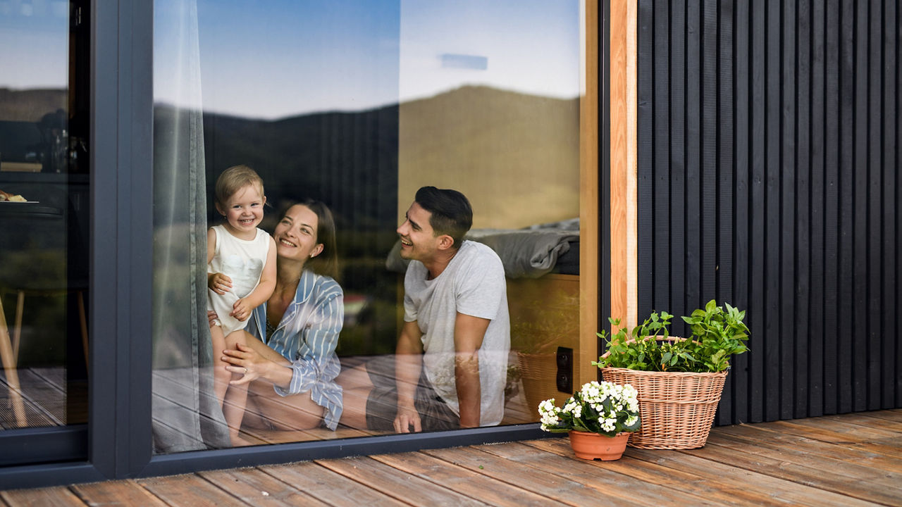 Familie mit Kind blicken durch das Terrassenfenter auf ihre Terasse