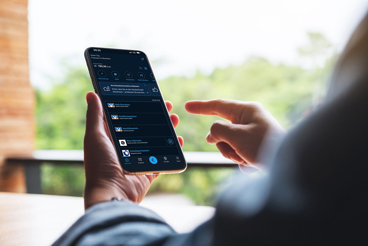Ein Smartphone mit einer Banking App wird ins Handy gehalten und bedient