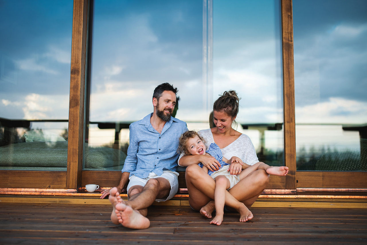 Familie sitzt auf der Terrasse auf dem Boden und lacht