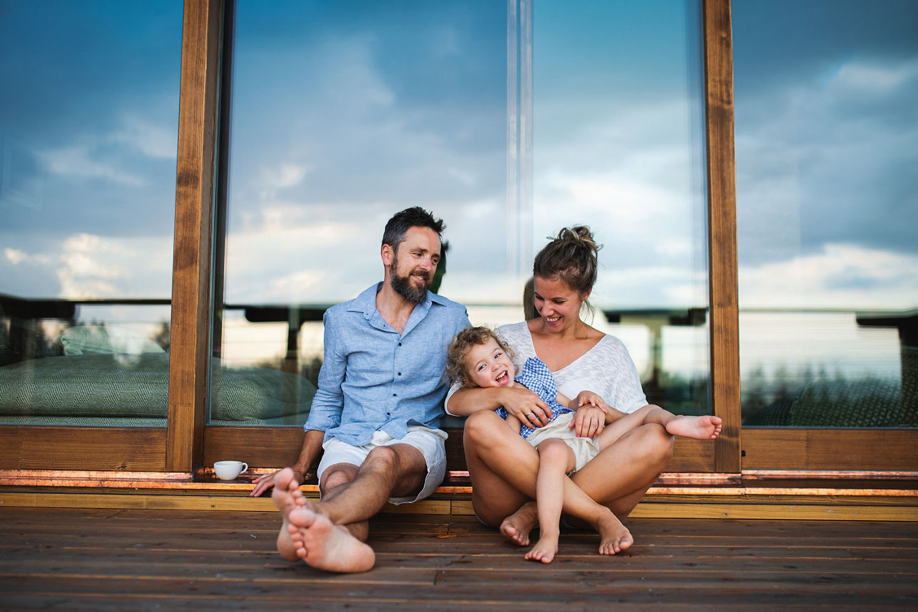 Familie sitzt auf der Terrasse auf dem Boden und lacht