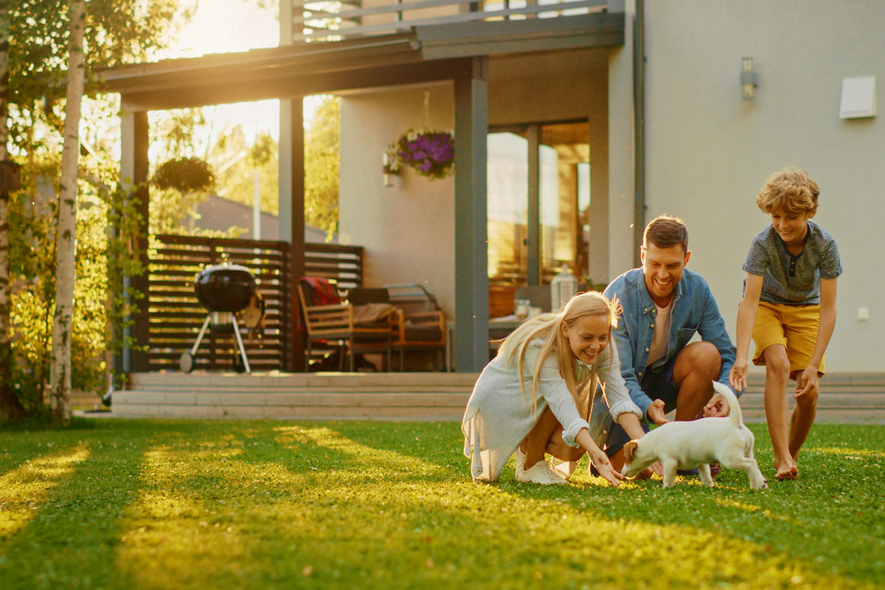 Familie mit Hund im Garten vor ihrem Haus