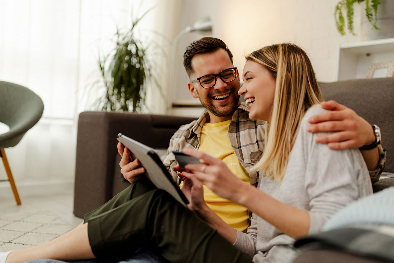 Mann und Frau sitzen mit Tablet auf der Couch