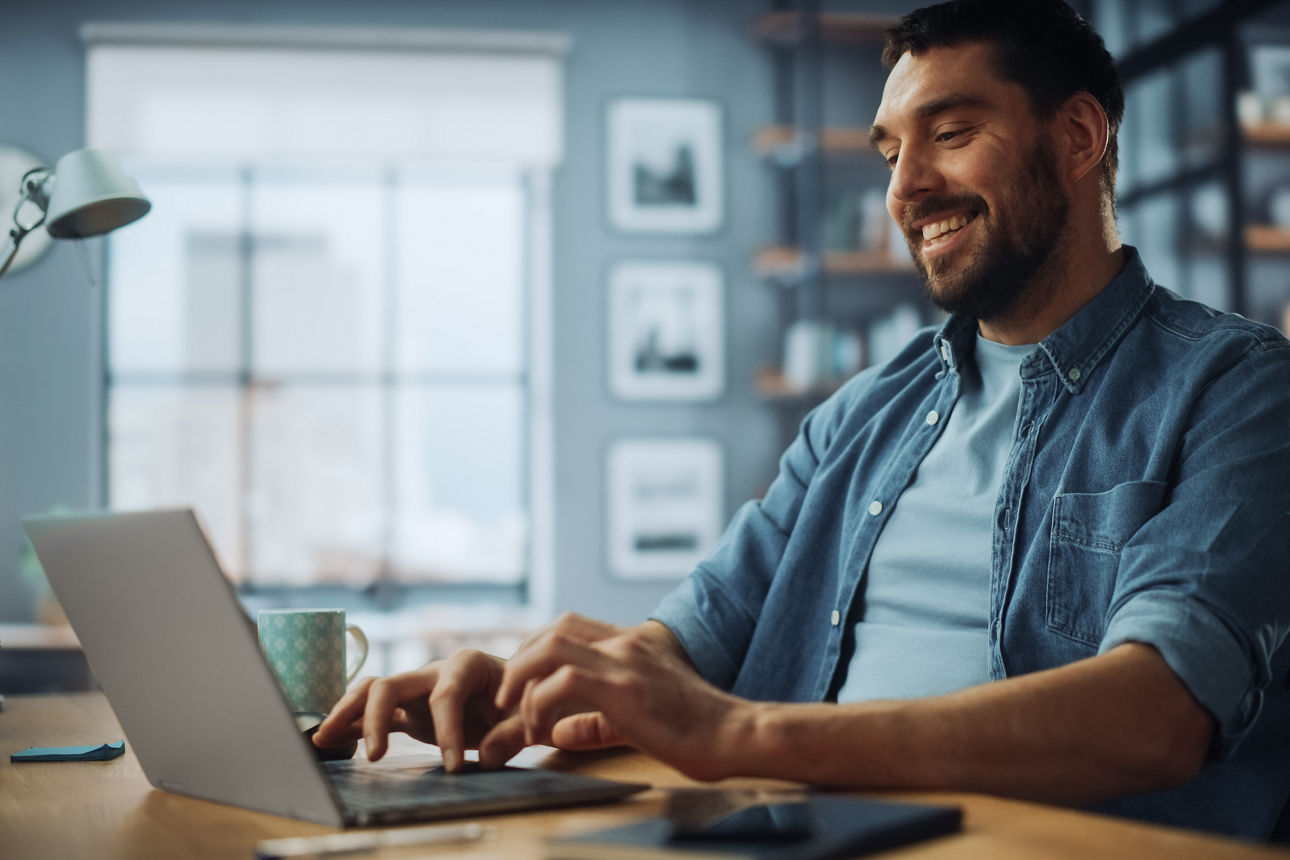 Mann sitz lächelnd am Laptop