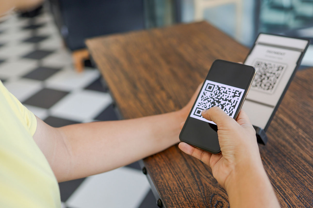 Eine Frau scannt mit einem Handy einen QR-Code