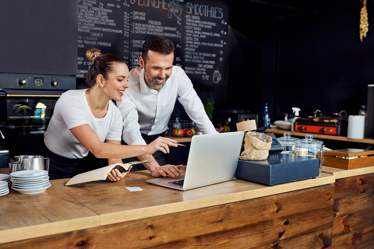 Ein Mann und eine Frau besprechen die Order hinter der Theke in einem Cafe