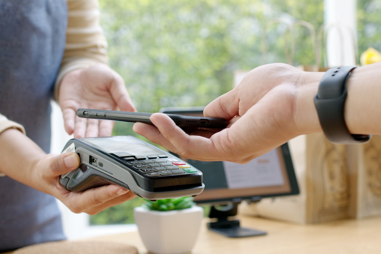 Ein Handy wird zum Bezahlen über ein EC Terminal gehalten