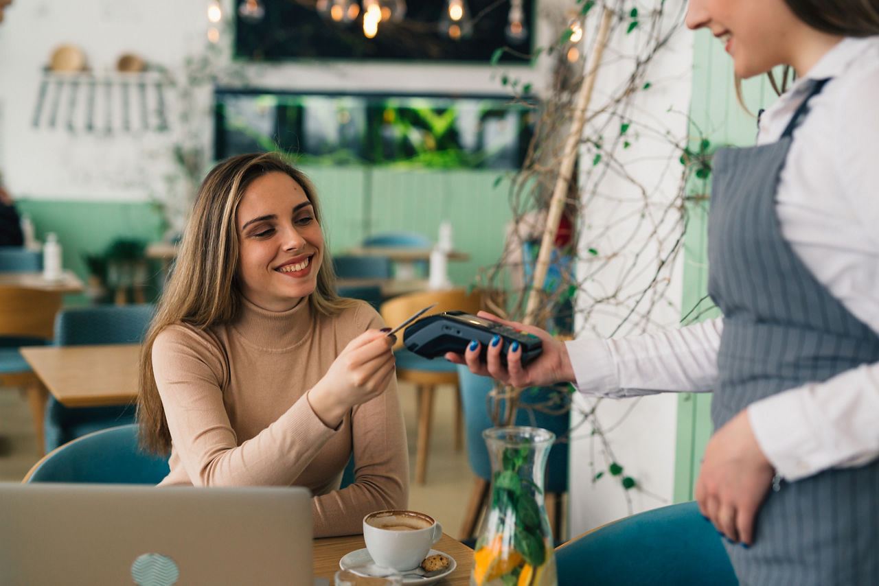Mann mit Kind auf dem Arm bezahlt an Marktstand mit Apple Pay