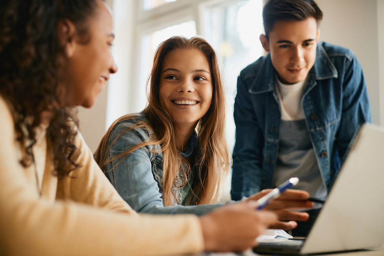 Darstellung von drei jungen Menschen, die vor einem Laptop sitzen
