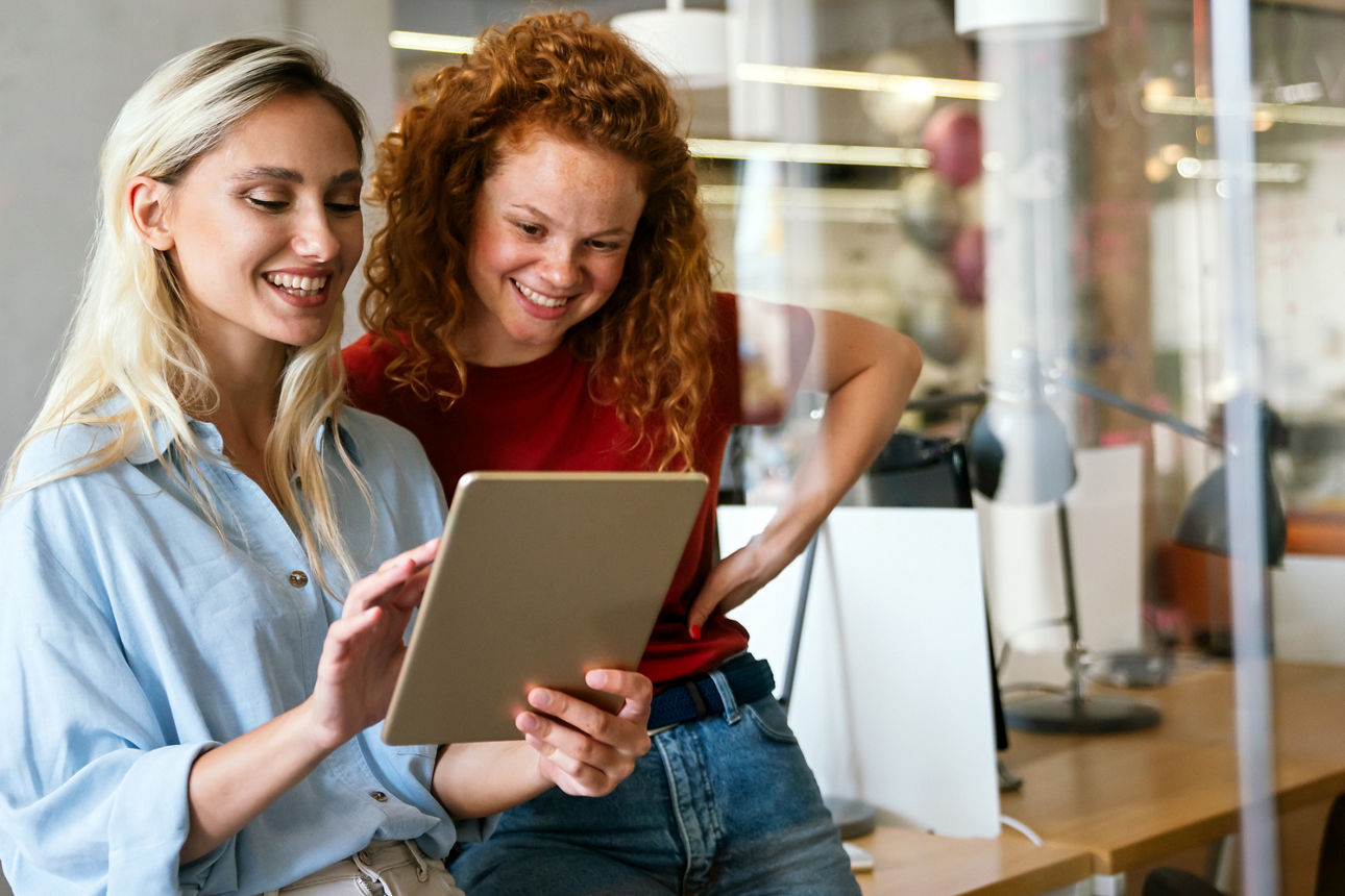 Darstellung von zwei jungen Frauen, die auf ein iPad schauen