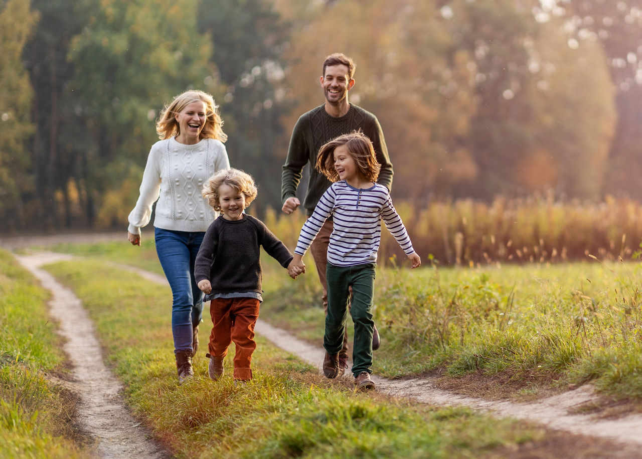 Eine Familie freut sich und läuft einen Feldweg entlang