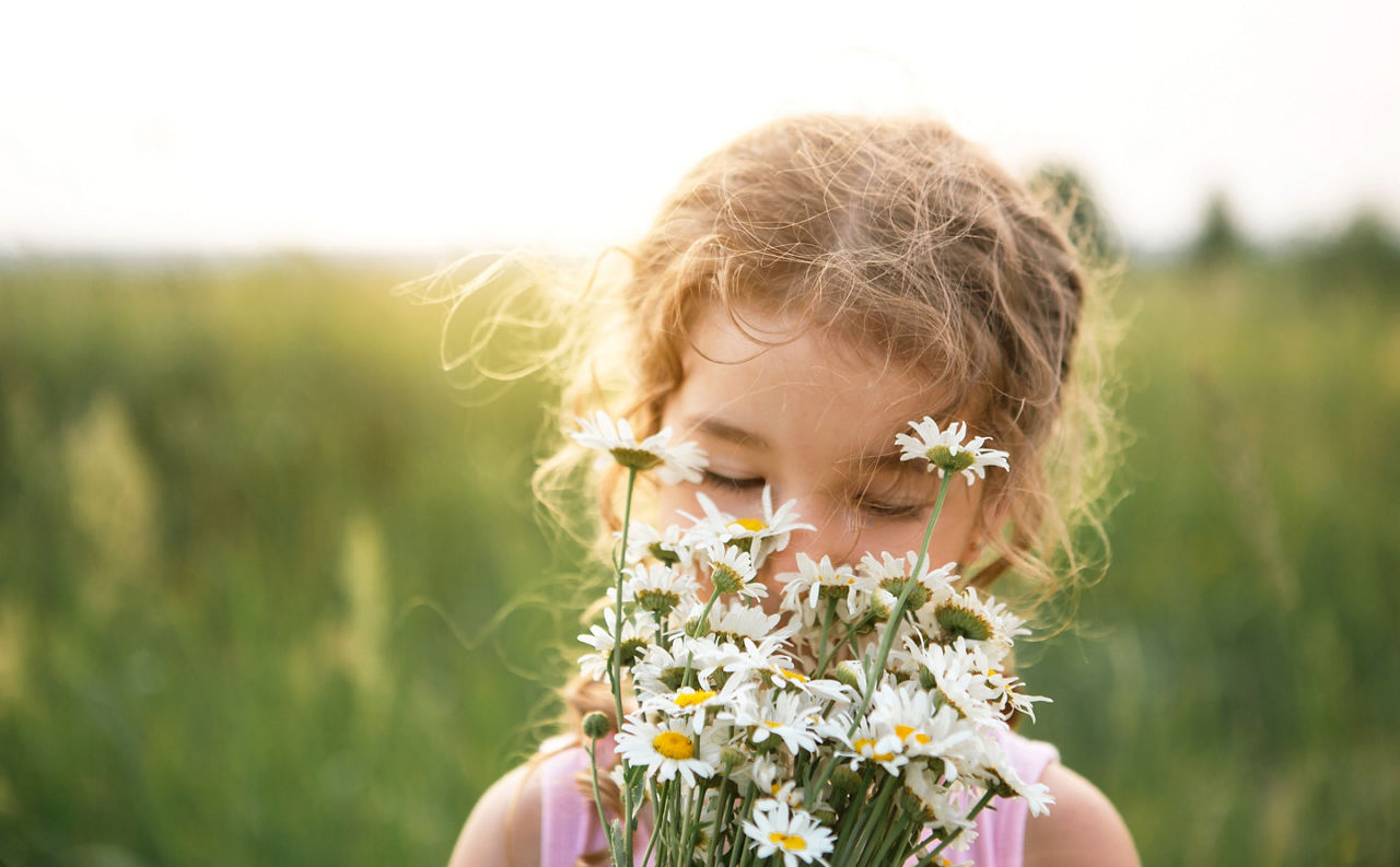 Kind riecht an Blumen