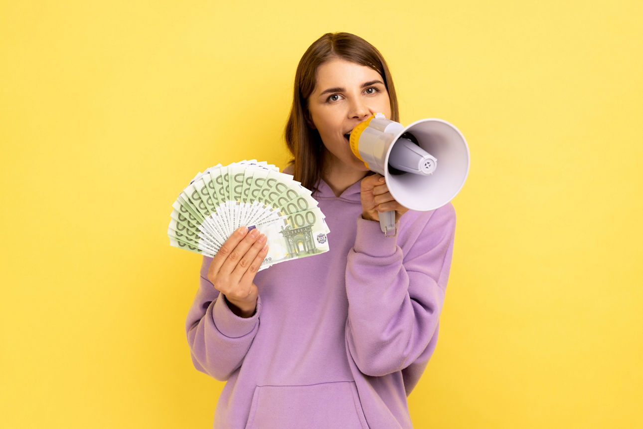 Frau hält einige Geldscheine und ein Megaphone in der Hand