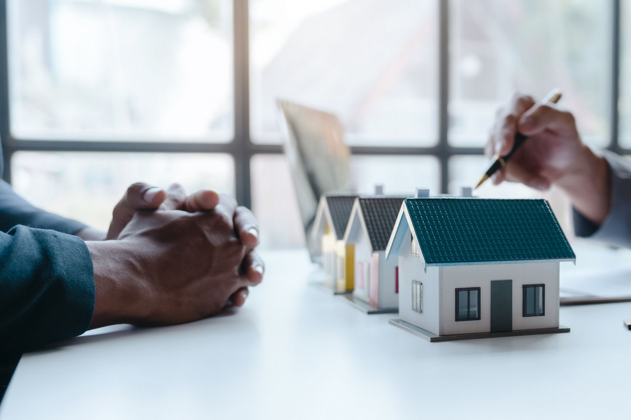 Zwei Geschäftsmenschen sitzen in einem Raum und diskutieren über Modellhäuser