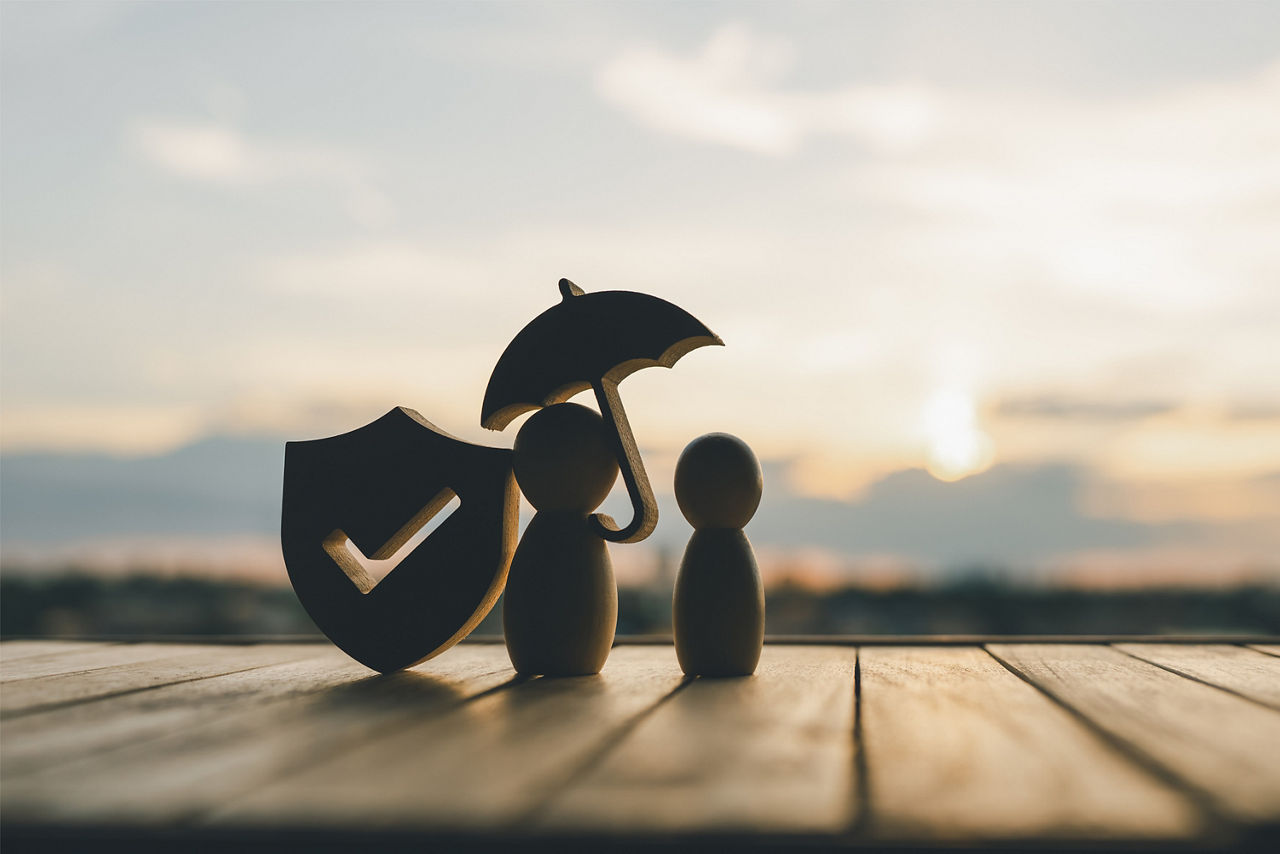 Zwei Figuren stehen unter einem Regenschirm