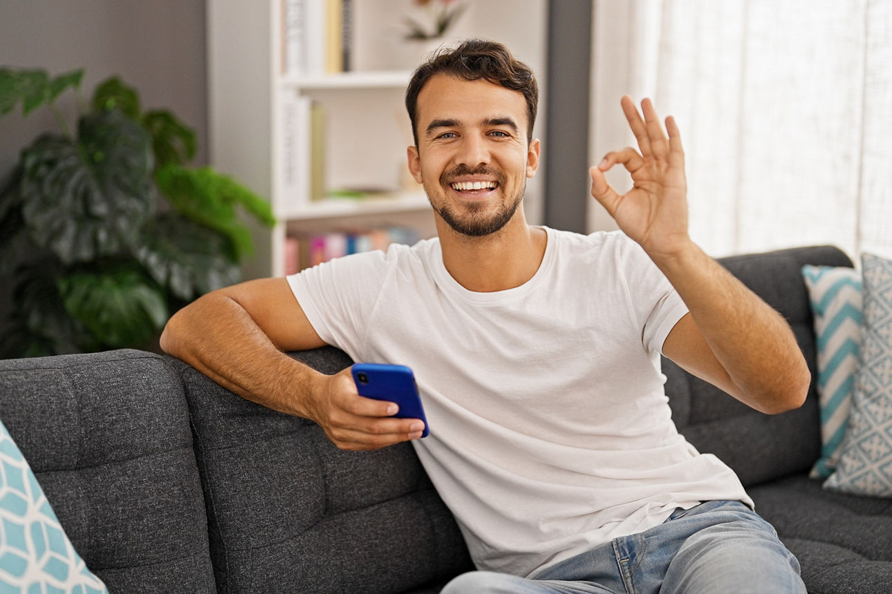 Mann auf Couch zeigt mit den Fingern eine Null
