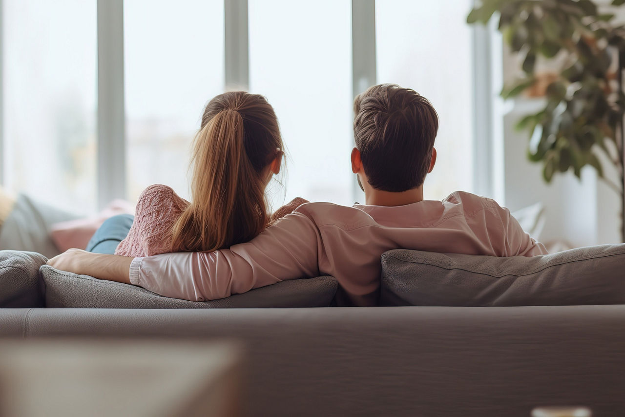 Paar sitzt auf der Couch und guckt aus dem Fenster