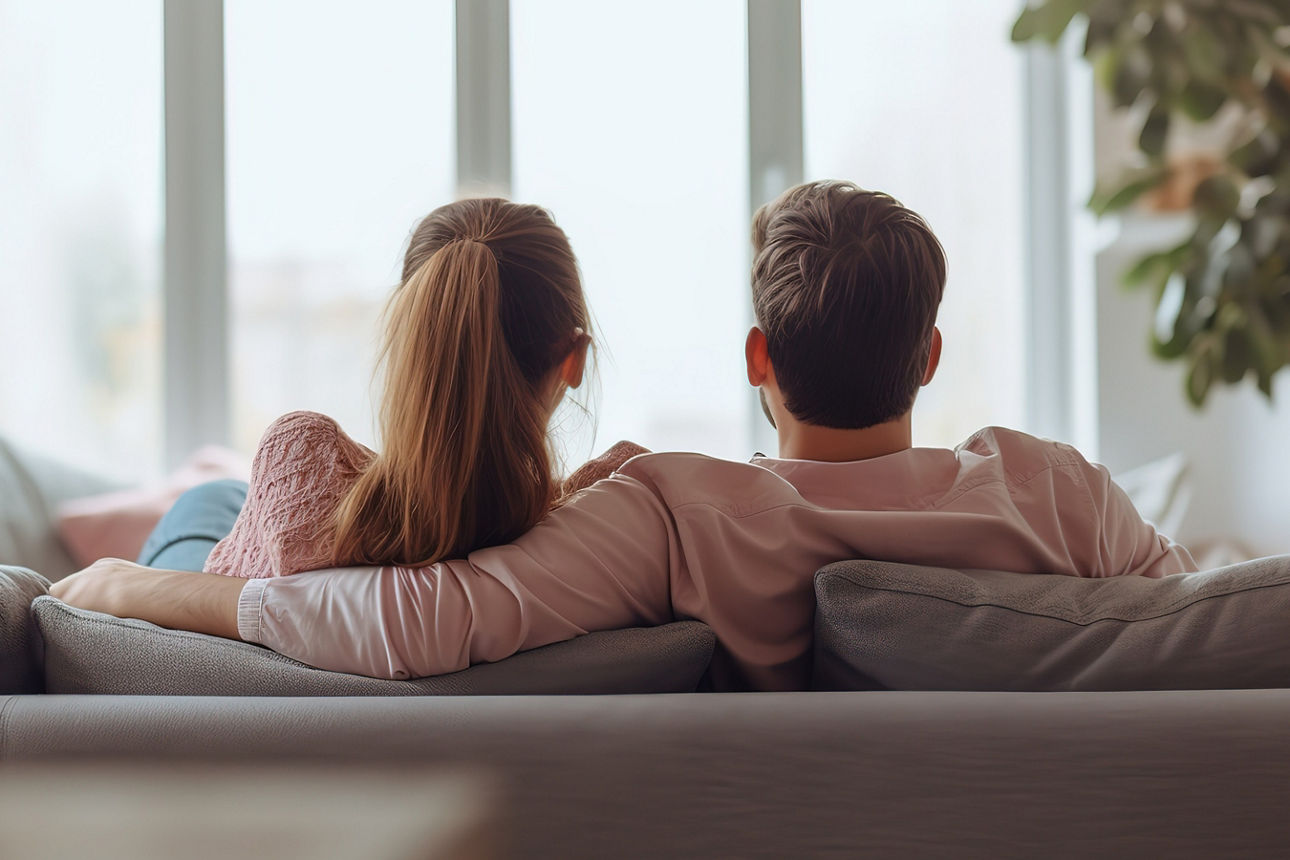 Paar sitzt auf der Couch und guckt aus dem Fenster