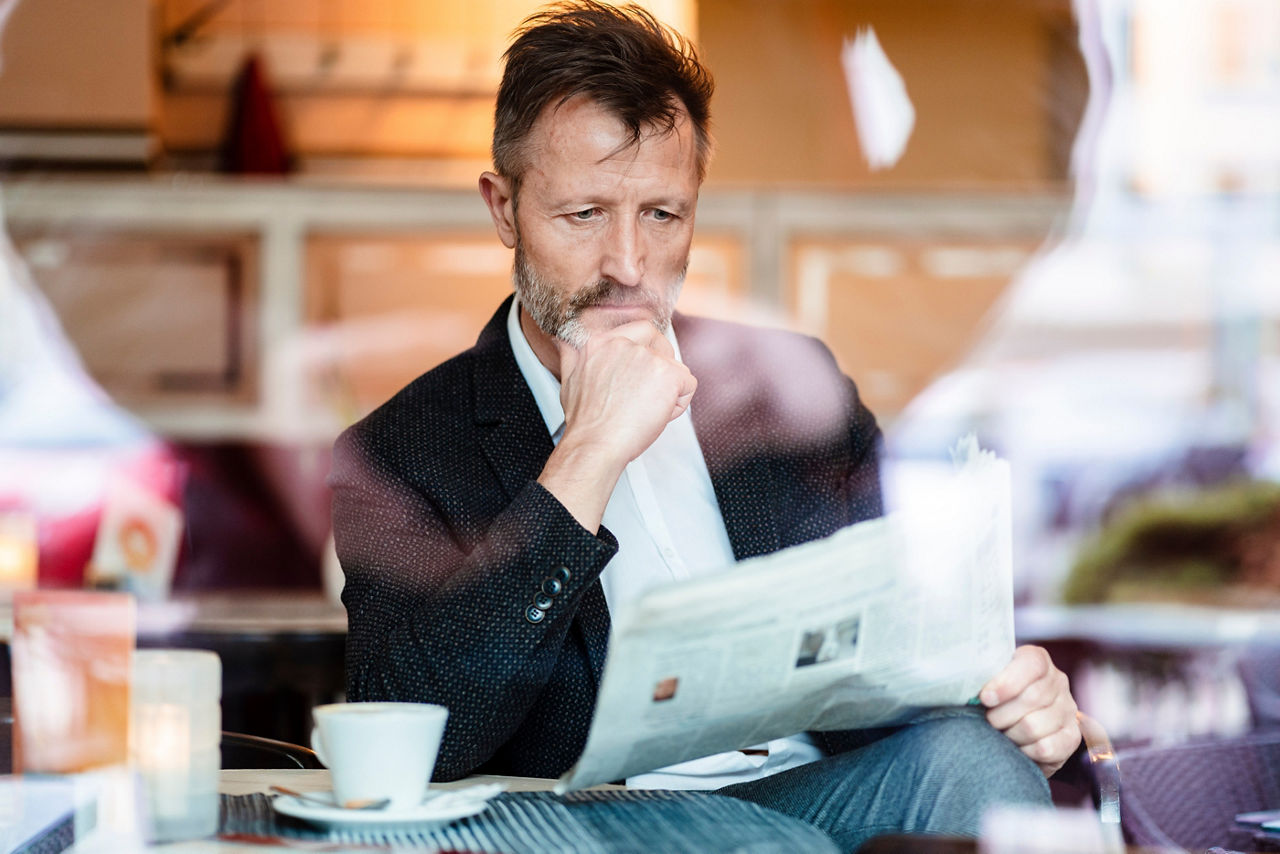 Darstellung eines Mannes, der in einem Café eine Zeitung liest