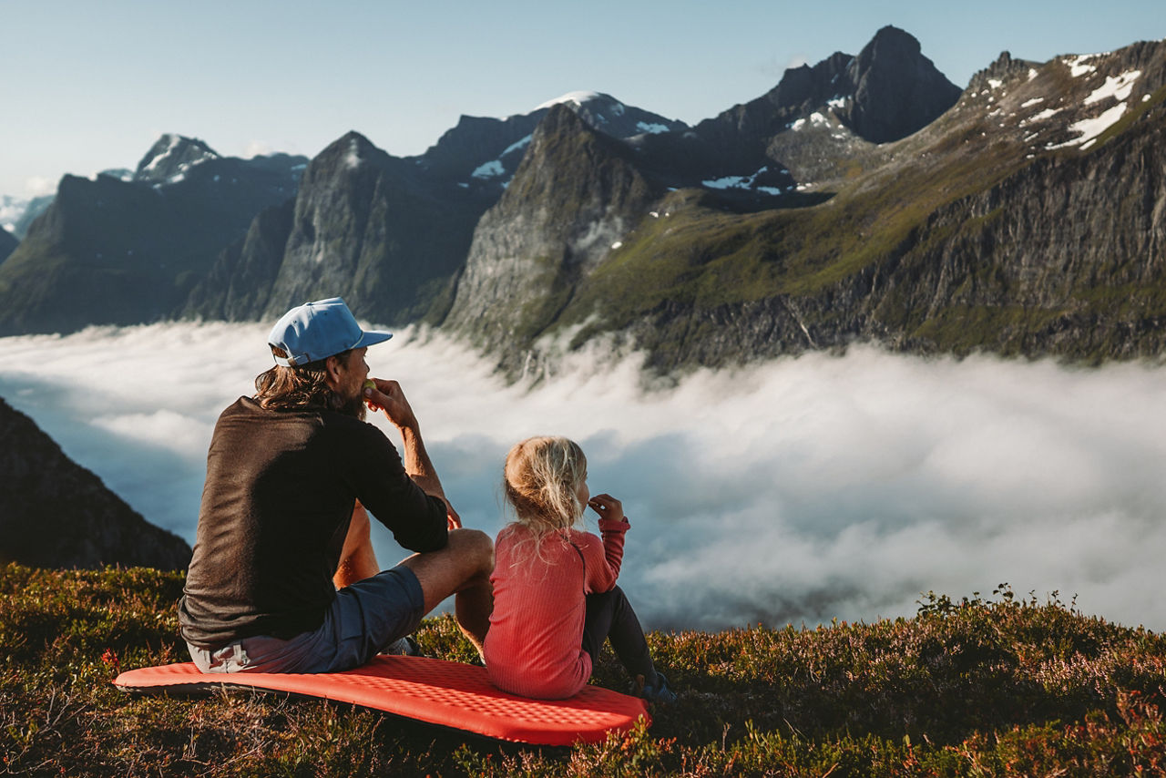 Family picnic father and daughter eating snacks in mountains travel vacations camping outdoor dad with child hiking together active lifestyle adventure trip parent and kid enjoying views in Norway 