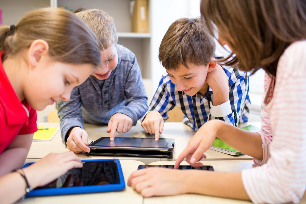 Gruppe von Schulkindern mit Tablets in einem Klassenraum 