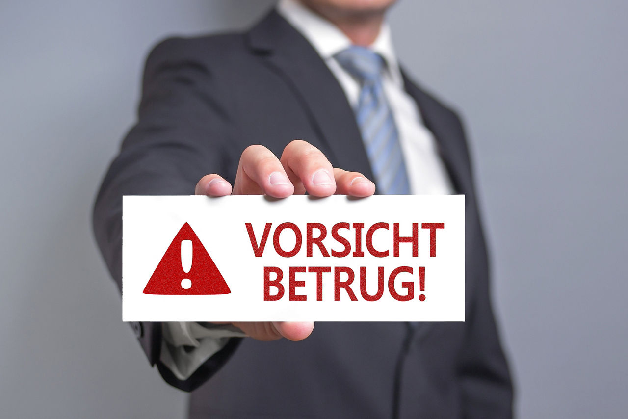 Mann zeigt Schild mit der Aufschrift Vorsicht Betrug!