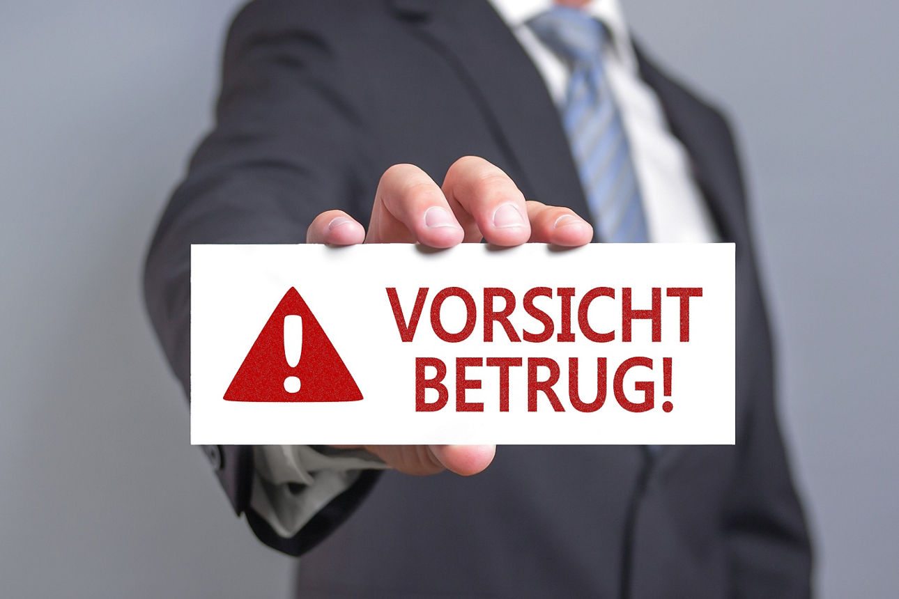 Mann zeigt Schild mit der Aufschrift Vorsicht Betrug!