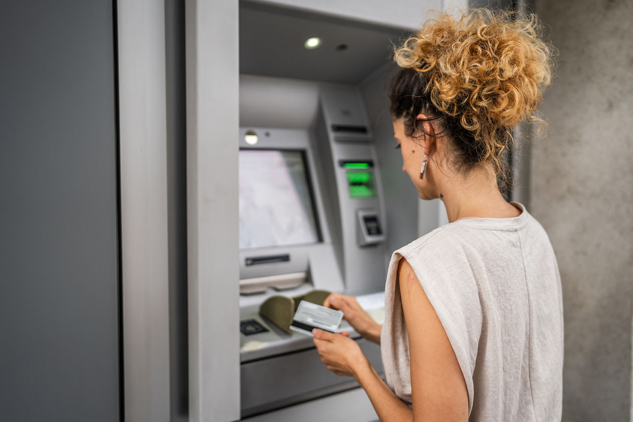 Frau steht am Geldautomaten