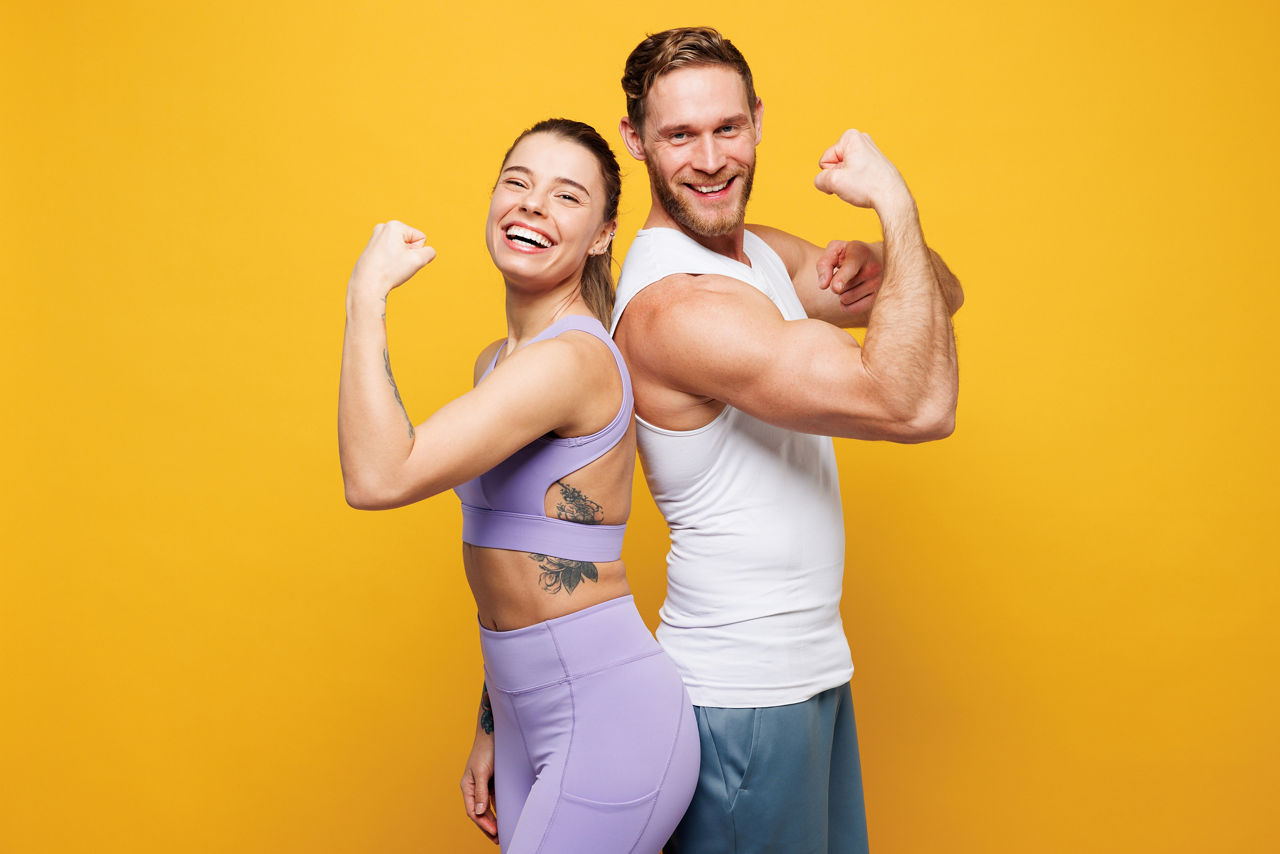 JungeFrau und junger Mann in Trainingsanzug stehen in einer starken Pose und zeigen ihren Bizeps.