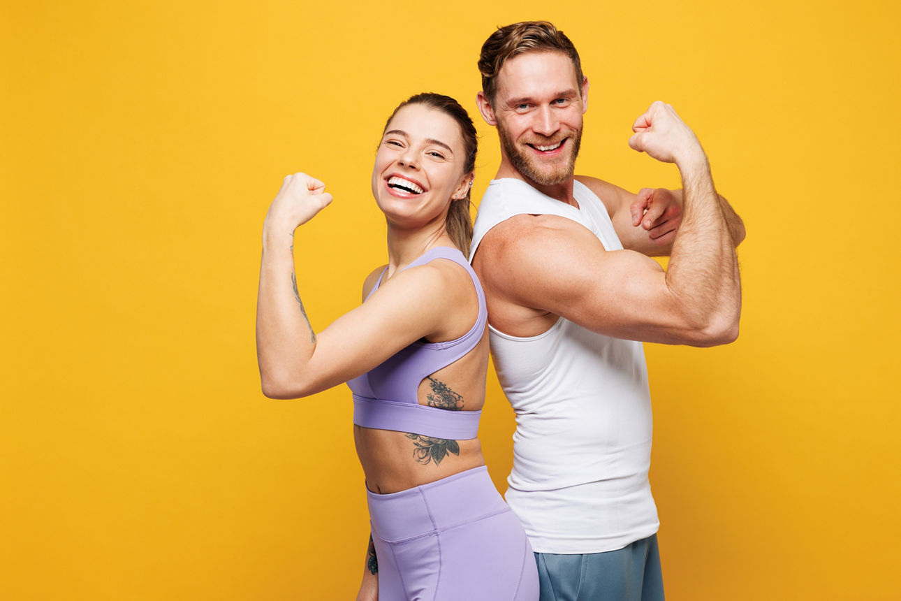 Eine junge Frau und ein junger Mann zeigen ihre Fitness und ihren Bizeps. 