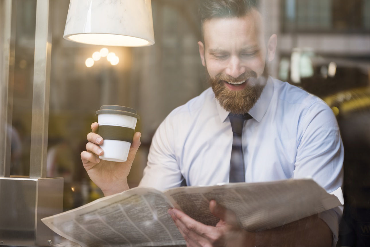Mann genießt einen Kaffee und liest Zeitung