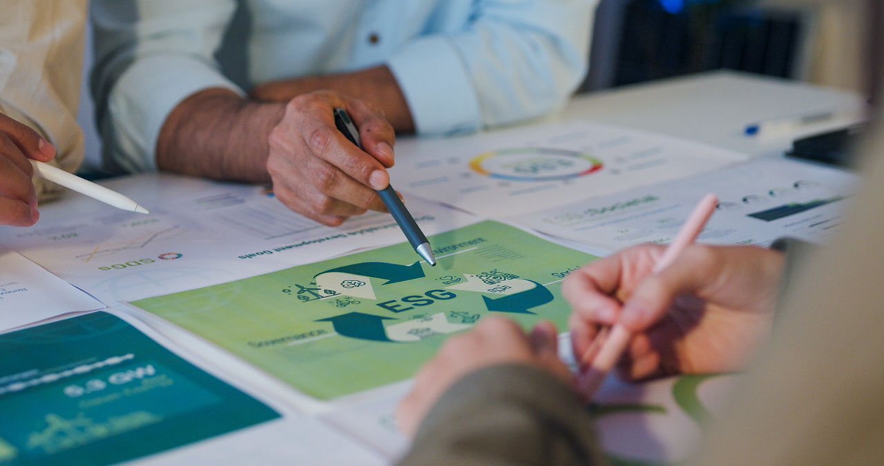 Hände mit Stiften in der Hand, die auf ein Blatt Papier zeigen auf dem ESG steht.