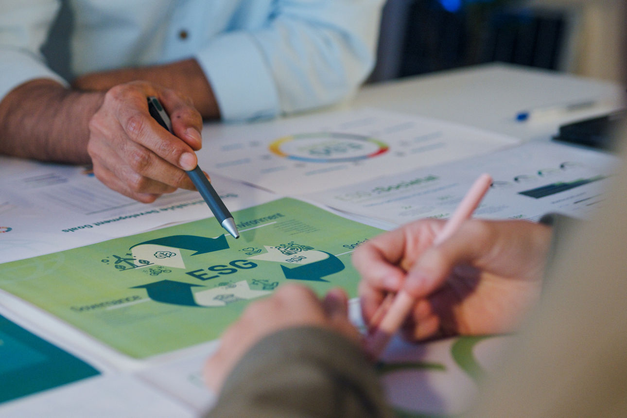 Hände mit Stiften in der Hand, die auf ein Blatt Papier zeigen auf dem ESG steht.