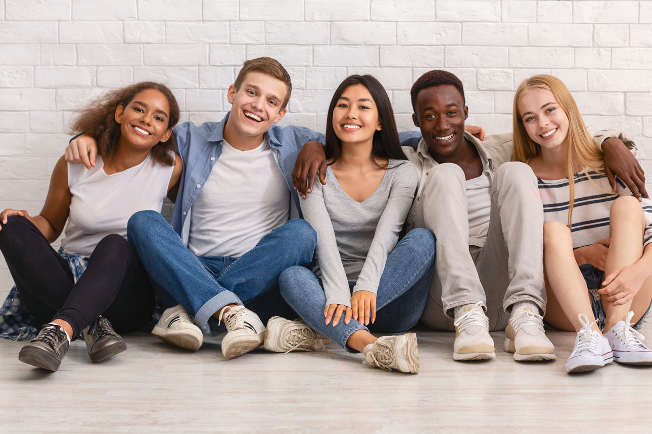 Jugendliche sitzen lachend auf dem Boden
