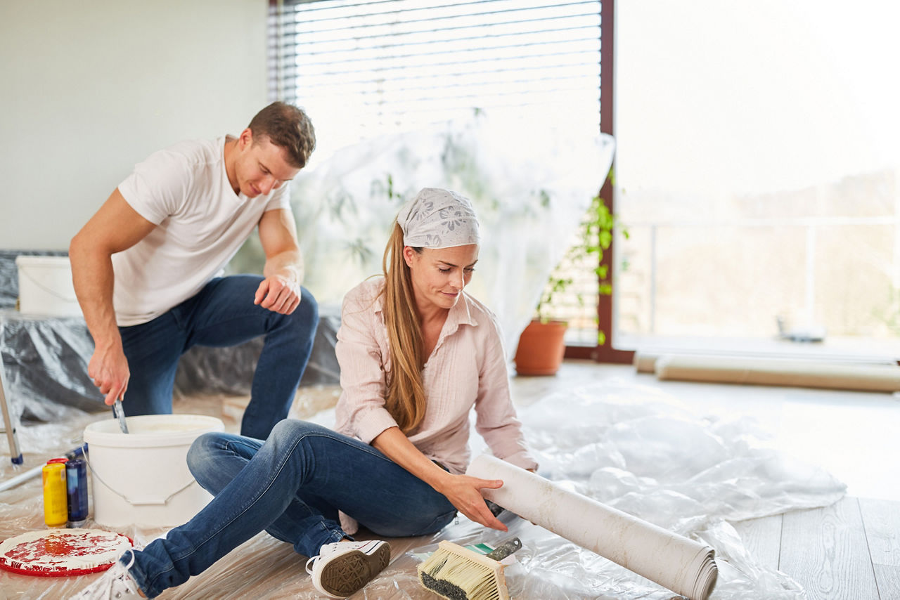 Paar im neuen Haus beim Renovieren und Tapezieren im Wohnzimmer