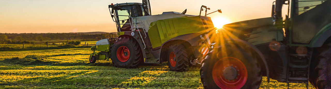 Zwei Traktoren auf Feld bei Sonnenuntergang