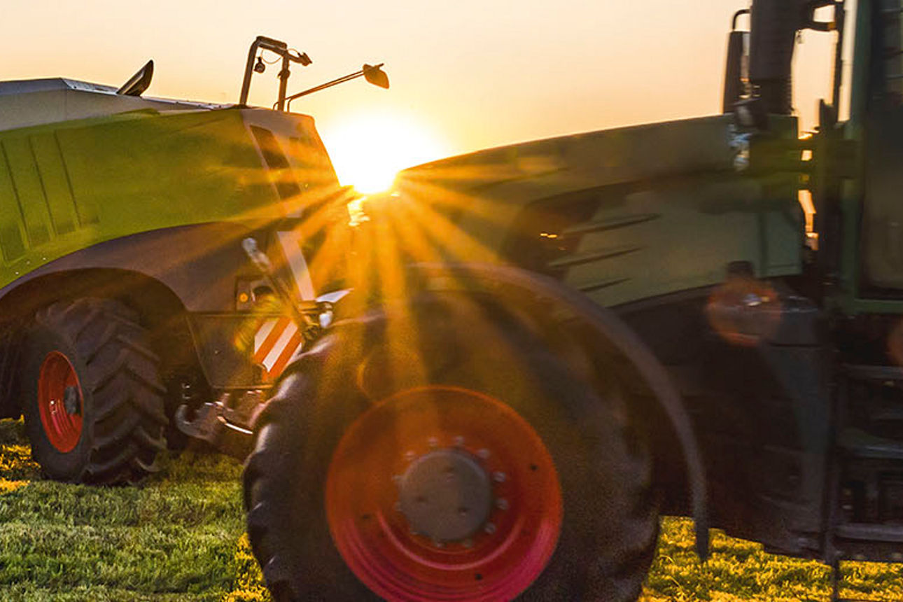 Zwei Traktoren auf Feld bei Sonnenuntergang