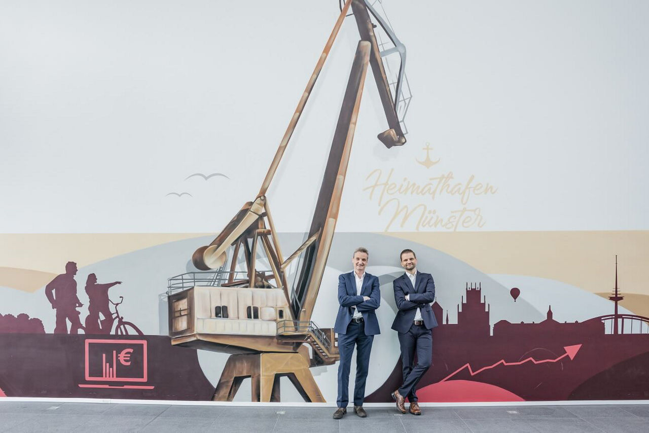 Vorstand steht vor dem Graffiti-Bild vom Hafen.